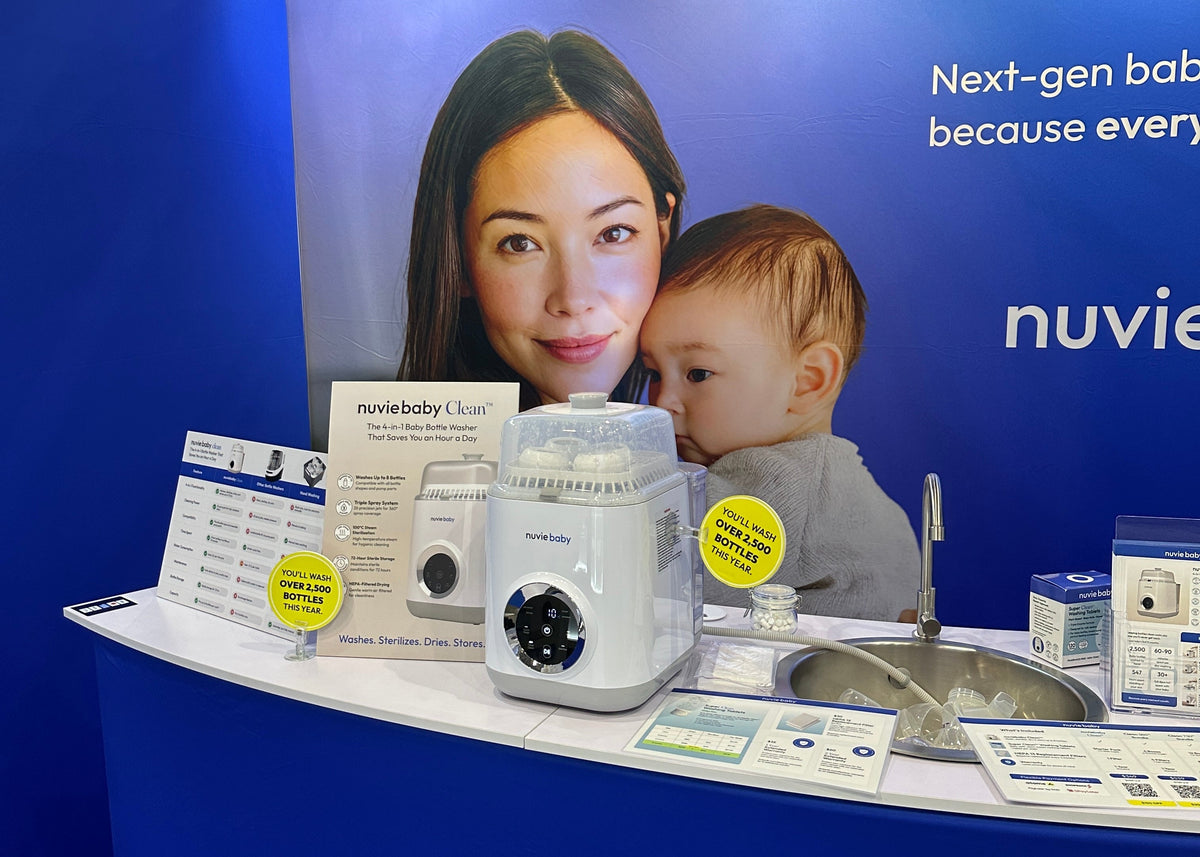 A nuviebaby Clean machine at the expo booth, loaded with sterilised bottles, yellow promotional discs behind it