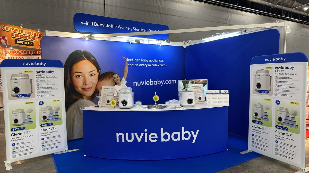 The nuviebaby expo booth, a Clean machine on a counter sink prop in front of a cobalt backdrop with product signage