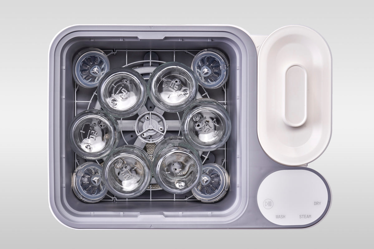 Six Philips Avent glass bottles loaded in the nuviebaby Clean Max washing basin, seen from above.